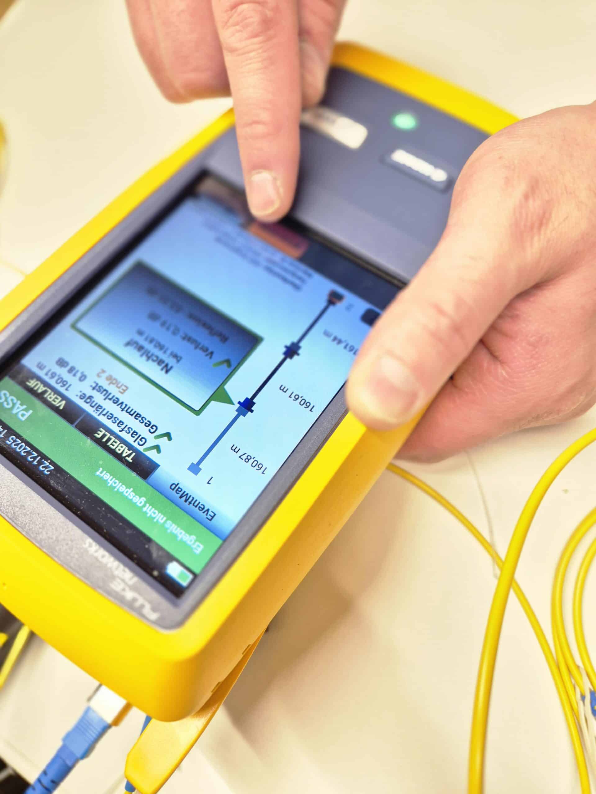 Nahaufnahme eines Fingers auf dem Touchscreen eines Fluke-Messgeräts, der die detaillierten Testergebnisse wie Glasfaserlänge und Gesamtverlust in der EventMap prüft.